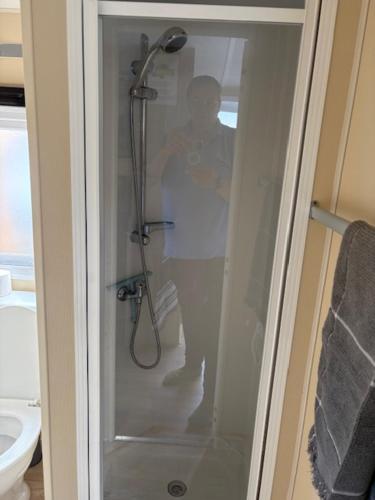 Un uomo in piedi in una doccia in bagno di Chalet De Duinberg a IJmuiden