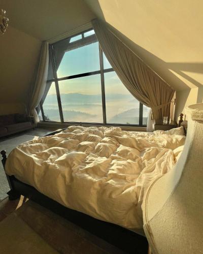 a bed in a room with a large window at Montesse Chalet- La noi la munte in Arada