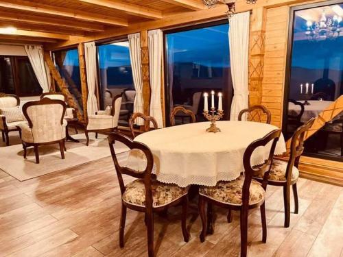 a dining room with a table and chairs and windows at Montesse Chalet- La noi la munte in Arada