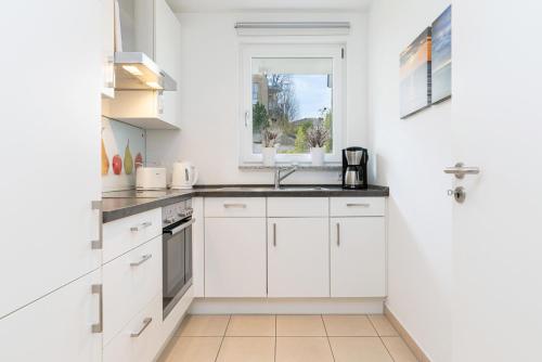 a white kitchen with a sink and a window at Meerurlaub in Laboe