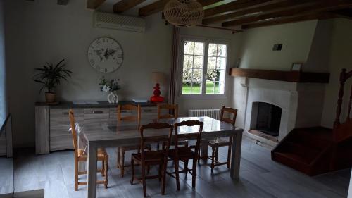 une salle à manger avec une table, des chaises et une horloge dans l'établissement Maison de Campagne à 2 min du zoo de Beauval, à Saint-Aignan