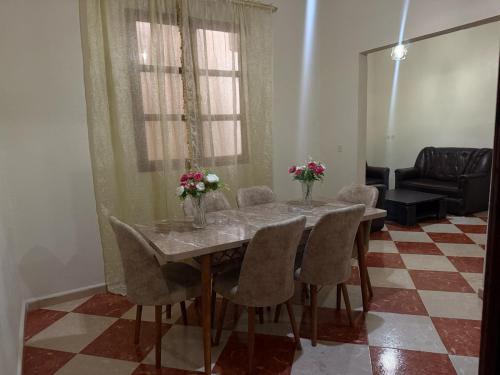 una mesa de comedor con sillas y flores. en Residence meknes, en Meknès