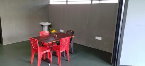 a red dining room table with red chairs in a room at Hidden Haven 1BR Coorg in Kushālnagar