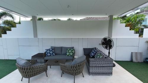 a patio with a couch and chairs and a staircase at Villa Kamala close to the beach in Kamala Beach