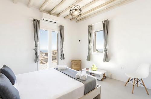 a white bedroom with a bed and a window at Ocean view villa in Mikonos