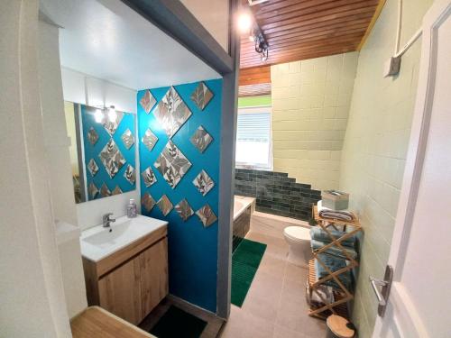 La salle de bains est pourvue d'un mur bleu, d'un lavabo et de toilettes. dans l'établissement Superb 80 m Duplex in Mulhouse Ideal Location, à Mulhouse