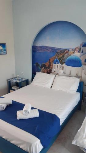 a bedroom with a large bed with a painting on the wall at Victoria's Blue studios in Siviri
