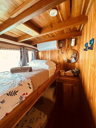 a bed in the middle of a room with wooden walls at Komodo Island Tour 3 Days with Best Komodo Tour in Pulau Kukusan