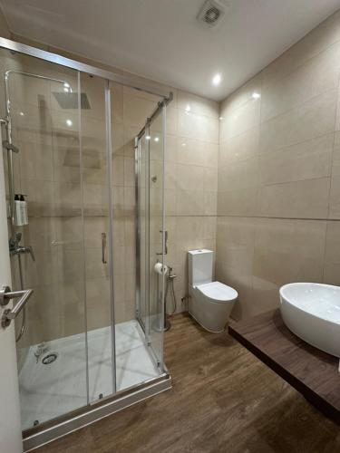 a bathroom with a shower and a toilet and a sink at Vestígios de Charme - Figueira Suits in Figueira da Foz