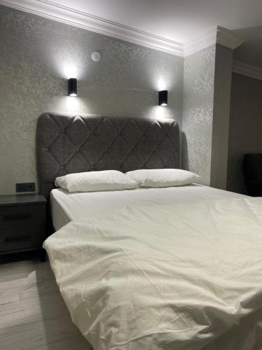 a bedroom with a white bed with two lights above it at pasific otel in Eskiömerler