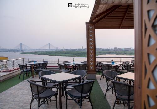 a row of tables and chairs on a patio next to the water at Nile Transportation hotel in Cairo