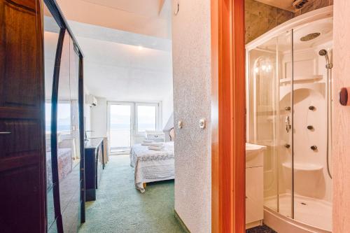 a bathroom with a shower and a bedroom at Hotel Vila Marco Polo in Slatine