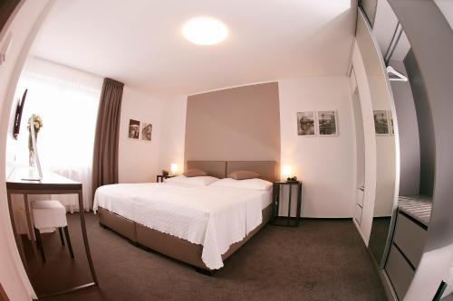 a bedroom with a white bed and a desk and a window at Villa na Vinici in Prague