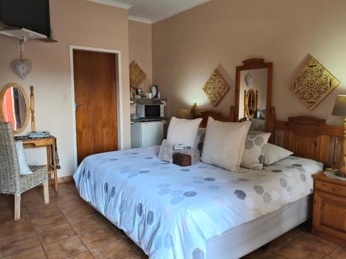 a bedroom with a large bed and a kitchen at Acacia Gastehuis in Kathu
