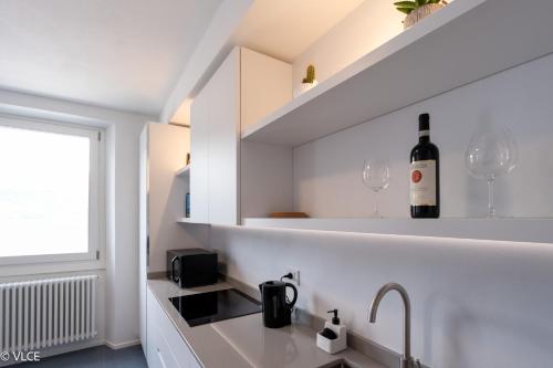 a white kitchen with a bottle of wine on a shelf at Casa Mael - Spacious lakefront flat in Lierna