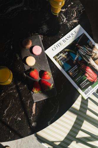 a table with a magazine and a plate of strawberries at Hotel Edouard VII in Biarritz