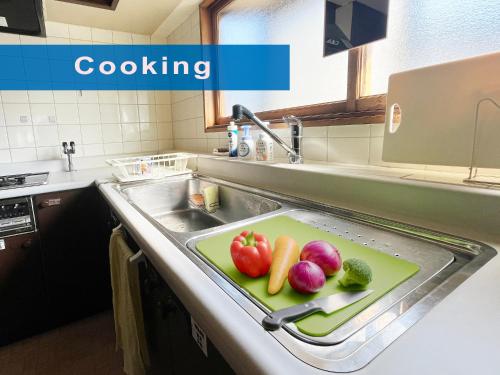 a sink with a cutting board with vegetables on it at Otaruya, Kitchen, Living Room, NETFLIX, 2 Rooms, Max 7PP, Free Parking in Otaru