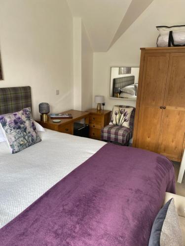 a bedroom with a large bed with a purple blanket at Clune House B&B in Newtonmore
