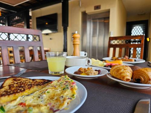 a table with plates of breakfast foods and a glass of orange juice at Golden Tulip Stone Town Boutique in Zanzibar City