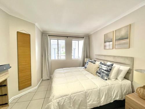 Un dormitorio blanco con una cama y una ventana. en Green Bay, en Plettenberg Bay