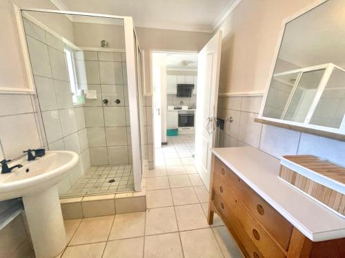 Un baño con ducha, lavabo e inodoro. en Green Bay, en Plettenberg Bay