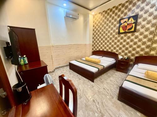 a room with two beds and a table and a desk at Khách Sạn Xuân Huỳnh 3 Sóc Trăng in Soc Trang
