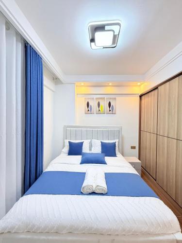 a bedroom with a large bed with blue pillows at Amari Suites in Gatunga