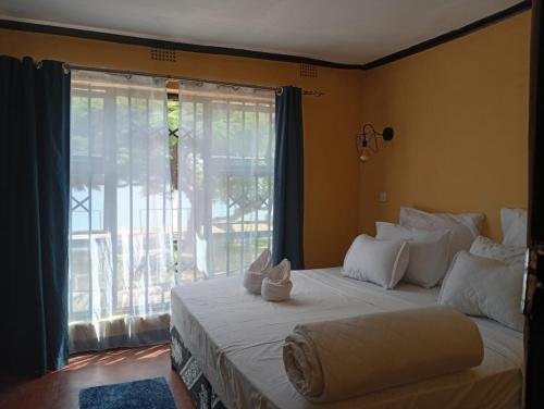 a bedroom with a bed with a large window at Capricorn by Quest-Cape Maclear in Chembe