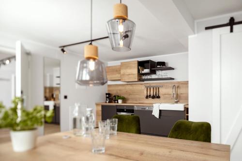 a kitchen with a wooden table with green chairs at Berg und Tal Hotel & Apartments in Braunlage