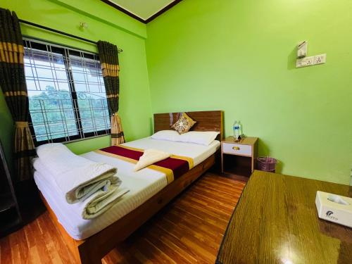 ein grünes Schlafzimmer mit einem Bett und einem Fenster in der Unterkunft Hotel Lekhnath View Tower and Eco Farm in Deorāli