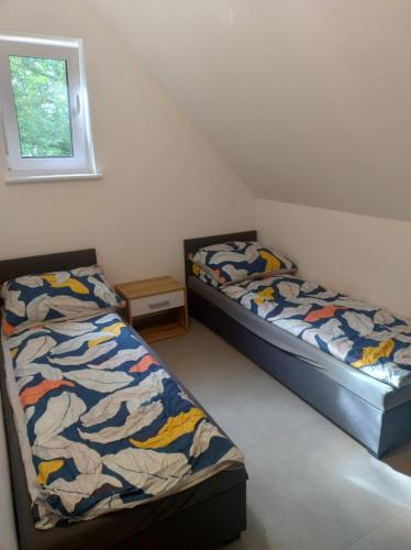 two beds in a small room with a window at Apartamenty - Domek Bobrowe Zacisze 3 in Janowice Wielkie