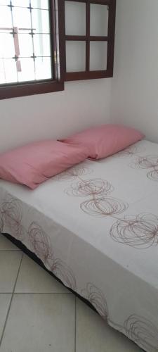 ein Bett mit einem rosa Kissen darüber in der Unterkunft Casa gourmet vista para o mar in Ilhabela