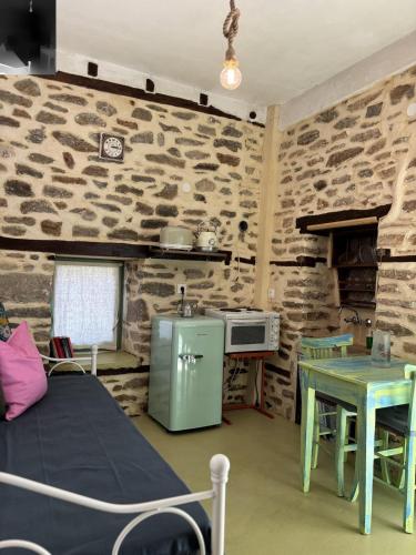 a room with a stone wall with a table and a bed at Atelies Stone House in Potamia