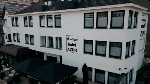a white building with a hotel yard sign on it at Boutique Hotel Azur in De Haan