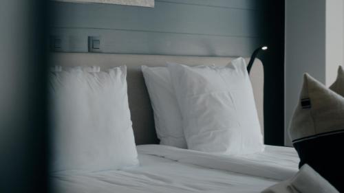 a bedroom with a bed with white pillows at Boutique Hotel Azur in De Haan