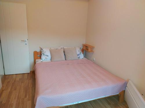 a small bedroom with a bed with pink sheets and pillows at Sorin Apartments Gevgelija in Gevgelija