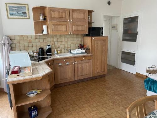 une cuisine avec des armoires en bois et un évier dans l'établissement KER MARY appartement lumineux 50 mètres de la plage, à Pornic