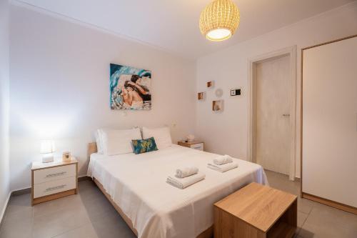a white bedroom with a large bed and a table at Stefanias apartment in Neos Marmaras