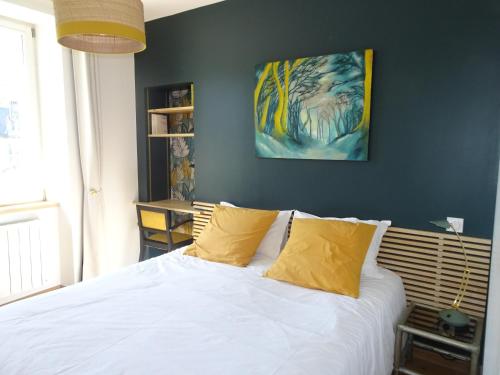 une chambre avec un lit avec des draps blancs et des oreillers jaunes dans l'établissement Le Richelieu 