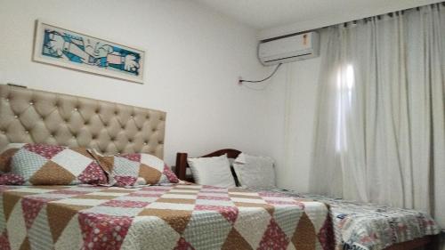 een slaapkamer met een bed met een deken en een raam bij Casa Mussurunga in Salvador