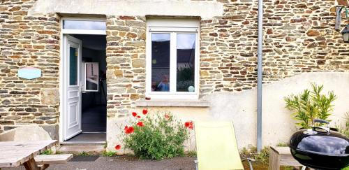 un bâtiment en briques avec une fenêtre, une table et des chaises dans l'établissement Les Frangins du Mont Saint Michel, à Pontorson