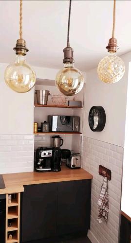 une cuisine avec trois lumières suspendues au plafond dans l'établissement Les Frangins du Mont Saint Michel, à Pontorson