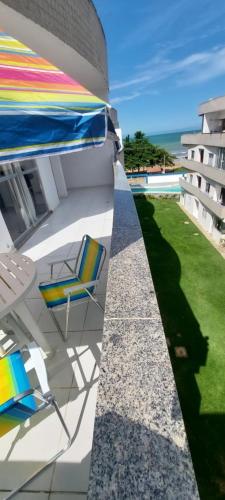 a patio with chairs and an umbrella on a building at Cobertura de Frente Para o Mar e Piscina Village das Ondas in Piúma