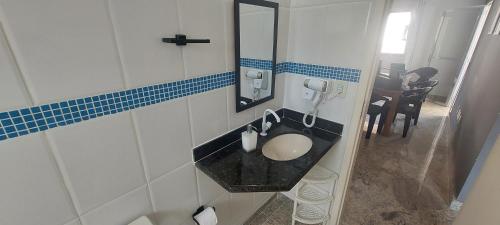 a bathroom with a sink and a mirror at Cobertura de Frente Para o Mar e Piscina Village das Ondas in Piúma