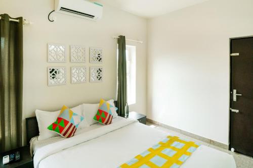 a bedroom with a white bed with colorful pillows at Super Hotel O Elegant KINGS PARK RESIDENCY in Cochin