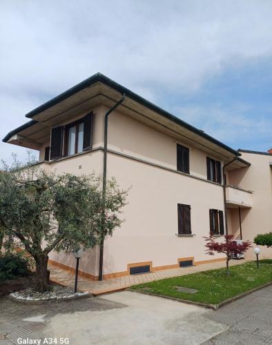 a white building with black windows and a tree at Casa Dante in Romano di Lombardia