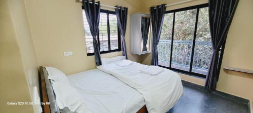 a small bed in a room with two windows at Shattaraka Home Stay in Jāmb