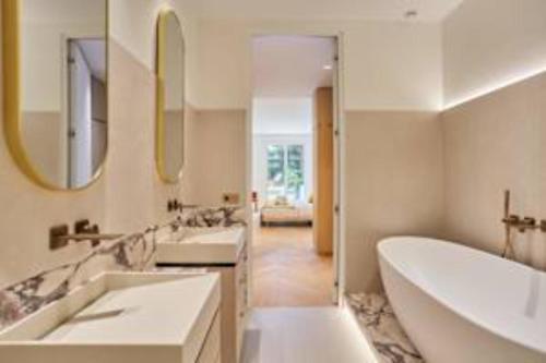 La salle de bains est pourvue de 2 lavabos, de 2 miroirs et d'une baignoire. dans l'établissement Sumptuous apartment with garden Arc de Triomphe, à Paris