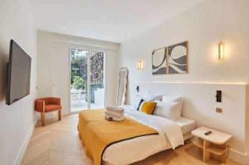 une chambre blanche avec un lit et une télévision dans l'établissement Sumptuous apartment with garden Arc de Triomphe, à Paris