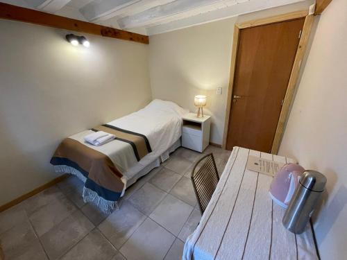 Un pequeño dormitorio con una cama y una mesa. en Green House B & B, en Villa La Angostura